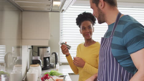 Video-of-happy-diverse-couple-preparing-meal-in-kitchen