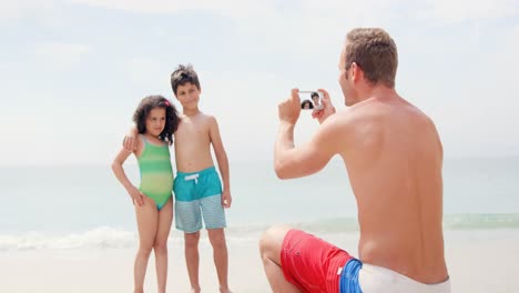 Father-taking-picture-of-his-children-on-the-beach