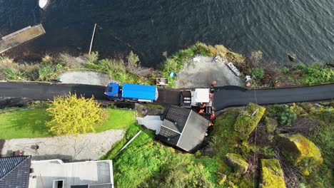 LKW-Füllt-Asphaltmaschine-Mit-Mehr-Asphalt-Auf-Norwegischer-Landstraße-In-Der-Nähe-Des-Meeres-–-Blick-Aus-Der-Vogelperspektive-Nach-Unten