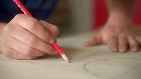 Artisan-Working-On-Artistic-Project-Using-Red-Pencil-Leads-And-Paper