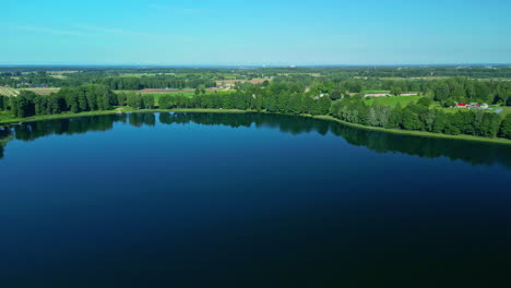 Drone-shot-of-trees-and-country-side-reflecting-off-of-a-lake-with-a-glassy-surface
