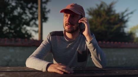 Young-man-sitting-down-outside-to-make-a-phone-call