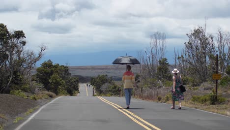 Zwei-Frauen-Laufen-An-Einem-Heißen-Hawaiianischen-Tag-Durch-Den-Verwüstungspfad-Des-Vulkan-Nationalparks-Mit-Blick-Auf-Den-Park-Im-Hintergrund