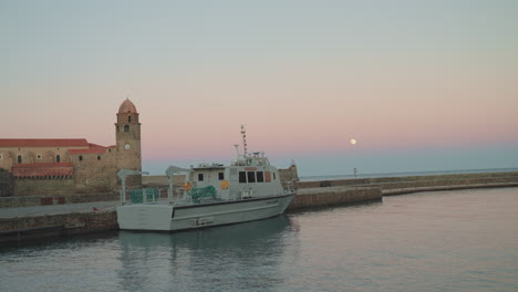 Dusk-at-Port-Collioure,-boat-docked,-Église-Notre-Dame,-sunset-colored-sky