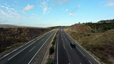Ein-Standbild-Einer-Geteerten-Straße-Mit-Autos,-Die-Durch-Eine-Klare-Ländliche-Landschaft-In-Spanien-Fahren