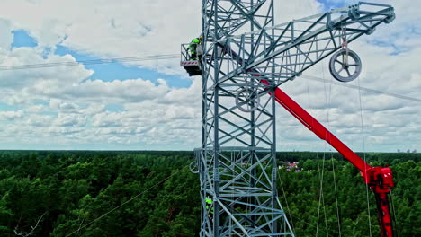 Luftschwenkaufnahme-Eines-Strommastes,-Während-Elektriker-Gefährliche-Wartungsarbeiten-Durchführen,-Um-Den-Strom-Wieder-Zum-Fließen-Zu-Bringen-Und-Die-Stadt-Mit-Energie-Zu-Versorgen