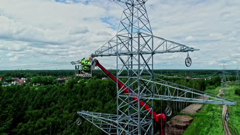 Luftaufnahme-Eines-Strommastes,-Während-Elektriker-Gefährliche-Wartungsarbeiten-Durchführen,-Um-Den-Strom-Wieder-Zum-Fließen-Zu-Bringen-Und-Die-Stadt-Mit-Energie-Zu-Versorgen