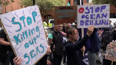 In-slow-motion-people-hold-up-placards-that-read,-“Stop-ocean-drilling”-and-“Stop-killing-our-seas”-during-the-Restore-Nature-Now-protest