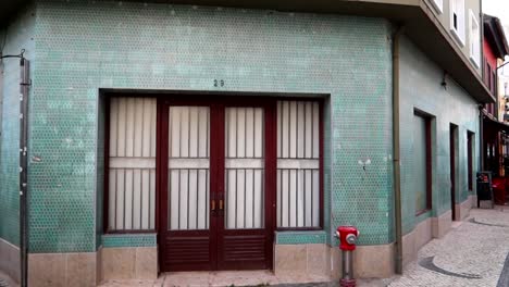 Schwenk-Nach-Rechts-Auf-Ein-Blau-Gekacheltes-Haus,-Während-Menschen-Auf-Der-Aveiro-Straße-Spazieren