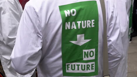 In-slow-motion-a-scientist-wears-a-white-coat-with-the-slogan-that-reads,-“No-nature,-no-future”