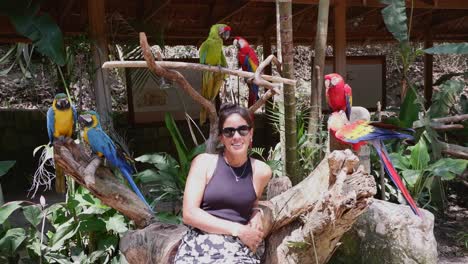 Pretty-Hispanic-woman-surrounded-by-colorful-Macaw-parrots-in-Honduras