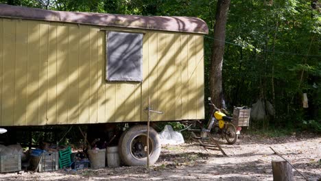 Old-yellow-metal-camping-trailer-in-woodland-off-grid-camping-scene