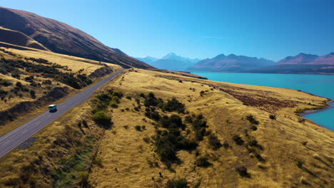Aerial-view-following-a-car-driving-along-the-scenic-mountain-road-to-Mount-Cook-in-the-Southern-Alps,-New-Zealand