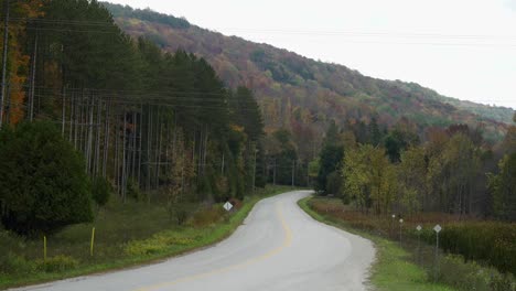 Remote-road-winding-through-hilly-landscape-on-an-overcast,-fall-day-in-Milton,-Ontario