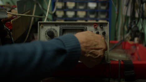 Close-up-of-elderly-male-hand-handling-old-oscilloscope,-no-face