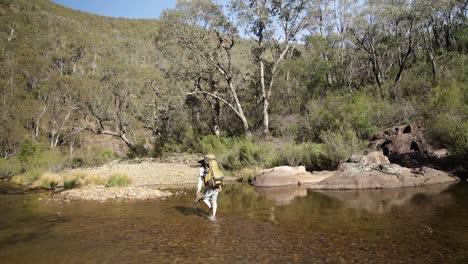 A-hiker-walks-accross-a-river-with-a-pack-on-the-Victorian-High-country