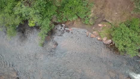 Riverbank-in-the-daytime,-water-running,-drone-shot