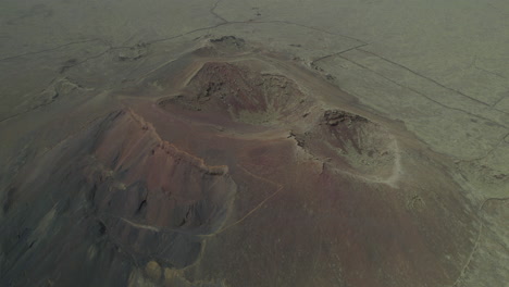 Vista-Aérea-En-órbita-Sobre-El-Cráter-Del-Volcán-Arena-En-La-Isla-De-Fuerteventura-En-Un-Paisaje-Desértico