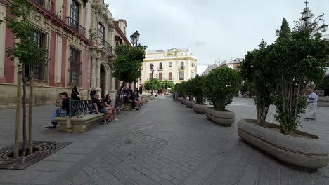 Gente-Sentada-En-Los-Bancos-En-El-Patio-Del-Parque-Cerca-De-La-Catedral-De-Sevilla-En-Sevilla,-España