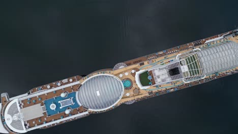 Overhead-aerial-of-a-cruise-ship-from-the-AIDA-line-moored-of-the-village-of-Gieranger-at-the-head-of-the-Geirangerfjord,-Norway