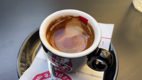 Nahaufnahme-Einer-Tasse-Espressokaffee-Auf-Einem-Teller-Und-Einem-Kleinen-Silbernen-Löffel,-Der-Auf-Dem-Teller-Neben-Der-Tasse-Ruht