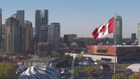 Eine-Kanadische-Flagge-Weht-Im-Wind-Mit-Der-Innenstadt-Von-Calgary,-Alberta-Im-Hintergrund