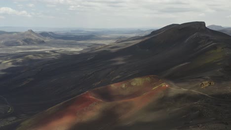 Toma-Lateral-Aérea-Del-Cráter-Del-Volcán-Raudaskal-Y-Paisaje-Geológico-En-La-Isla-De-Islandia-En-Segundo-Plano.