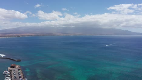 Wide-aerial-descending-shot-of-the-crystal-clear-waters-of-Maalaea-Bay-and-Haleakala-from-West-Maui,-Hawai'i