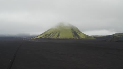 Aerial-approaching-shot-of-green-Maelifell-Volcano-on-Iceland-surrounded-by-dense-Clouds-and-fog