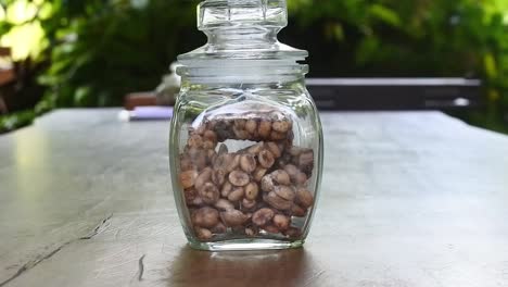 Tilt-up-shot-of-authentic-Indonesian-luwak-coffee-in-a-glass-jar-on-a-wooden-table