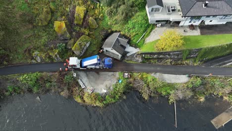 Steady-high-angle-aerial-view-of-workers-renewing-asphalt-on-seaside-private-narrow-road