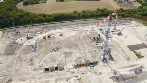 Aerial-drone-rotating-shot-over-a-construction-site-alongside-cranes-and-JCB-working-on-a-sunny-day
