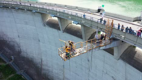 Personal-De-La-Plataforma-De-Puenting-Preparando-A-Una-Mujer-Para-Saltar-Mientras-La-Gente-Observa-El-Puente-De-La-Presa-En-Austria