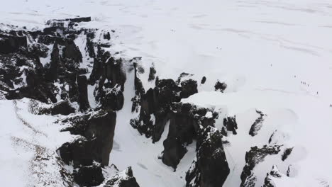 Drone-shot-circling-around-a-snowy-gorge,-cloudy-winter-day-in-Iceland