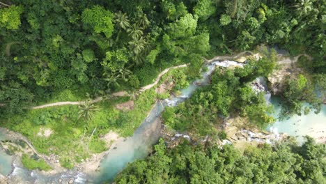 People-at-Kawasan-falls-in-Badian,-cebu-with-Matutinao-River-flowing-along-lush-jungle-trail