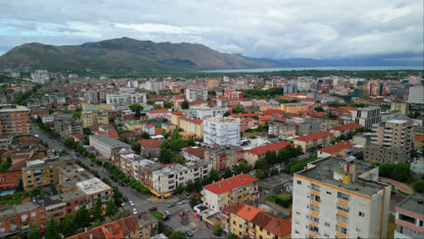 Aerial-drone-forward-moving-shot-over-city-buildings-on-both-sides-of-a-road-in-Shkoder-or-Scutari-in-northwestern-Albania-on-a-cloudy-day