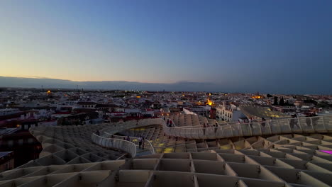 High-angle-shot-of-tourists-walking-on-Las-Setas-de-Sevilla,-also-known-as-Metropol-Parasol,-Seville,-Spain-during-evening-time