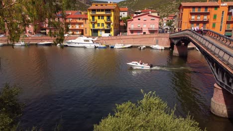 Boat-passing-down-bridge-in-river-Temo,-Bosa-touristic-town-in-Sardinia,-static