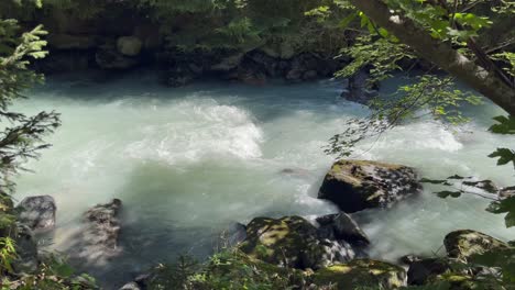 Detail-of-Mountain-river-with-blue-water-flowing-in-slow-motion-in-a-stream-in-Aosta-valley