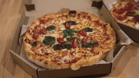 Gleitschuss-Von-Köstlichen-Italienischen-Pizzen,-Die-In-Kartons-Auf-Dem-Tisch-Geliefert-Werden