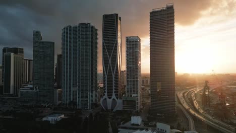Panorama-Drohnenaufnahme-Der-Innenstadt-Von-Miami-Bei-Sonnenuntergang,-Wolkenkratzern-Und-Autobahnverkehr,-USA