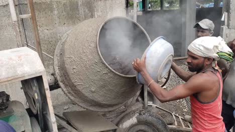 Footage-of-a-diesel-concrete-mixer-pouring-wet-cement-into-a-wheelbarrow-at-a-construction-site-in-India