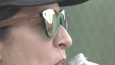 woman-opening-mouth-and-drinking-water-from-waterbottle,-close-up-during-beach-padel-match-with-sunny-weather