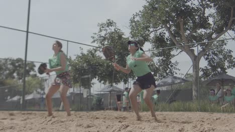 Frontale-Zeitlupenaufnahme-Von-Zwei-Frauen,-Die-Bei-Sonnigem-Wetter-Padel-Spielen,-Und-Mädchen,-Die-In-Shorts-Und-Wettkampftrikots-Ein-Padel-Match-Spielen