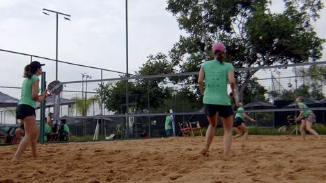 Padel-Wettbewerb,-Freundinnen-Spielen-Ball-Im-Padel-Match,-Schlagen-Und-Springen-Auf-Dem-Padel-Sandplatz-Am-Sonnigen-Strand