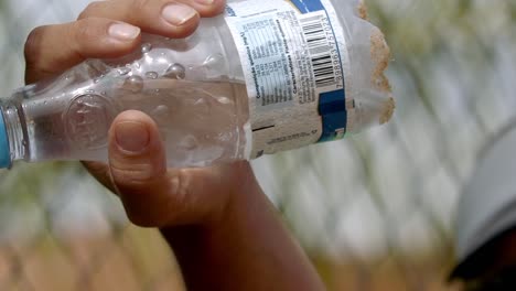 Mann-Trinkt-Wasser-Aus-Einer-Wasserflasche,-Nahaufnahme-Während-Eines-Padel-Spiels-Am-Strand-Bei-Sonnigem-Wetter