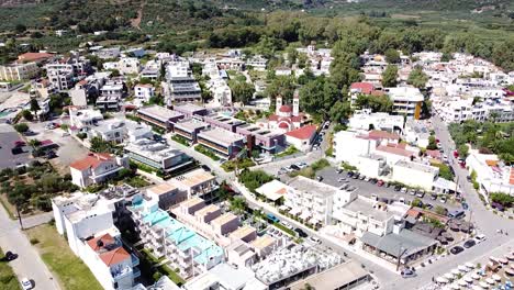 Bright-white-buildings-of-coastal-Crete-township,-aerial-view