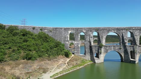 Pan-across-historic-old-bridge-crossing-green-river,-aerial-trucking-pan