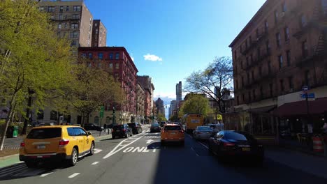Pov-shot-from-car-showing-taxi-on-street-in-New-York-City-during-blue-sky-and-sunlight-in-spring