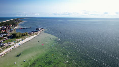 Luftaufnahme-Aus-Der-Vogelperspektive,-Die-Kitesurfer-An-Der-Ostsee-Mit-Sandstrand-An-Einem-Sonnigen-Tag-In-Polen-Zeigt